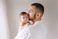 Fathers Day holiday. Bearded Caucasian father kissing newborn baby girl. Parent holding rocking child daughter son on hands. Royalty Free Stock Photo