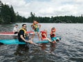 Fathers with kids swimming on paddle board on lake. Dads with children doing sport summer water activity outdoors. Seasonal Royalty Free Stock Photo