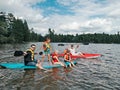 Fathers with kids swimming on paddle board on lake. Dads with children doing sport summer water activity outdoors. Seasonal Royalty Free Stock Photo