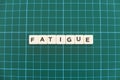 Fatigue word made of square letter word on green square mat background