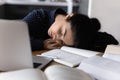 Fatigued young mixed race woman sleeping at workplace among books Royalty Free Stock Photo