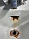 Faucet Dripping in a Porcelain Sink with Rusty Drain