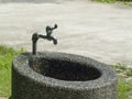 A faucet that shines with sunlight on a stone washbasin outdoors in a park