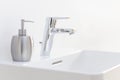 Faucet with tap and liqid soap in bright white bathroom