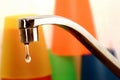 Faucet and waste of water with colorful glasses on background Royalty Free Stock Photo