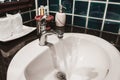 Faucet in a white sink in a bathroom with blue wall tiles Royalty Free Stock Photo