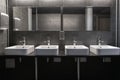 Faucets with washbasin in public restroom in grey colors