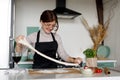 Favorite hobby is cooking pizza. Happy young woman stretching dough in the kitchen