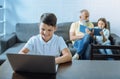 Smart youngster grinning widely while working on laptop