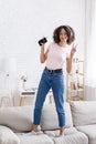 Favorite music at home during self-isolation. Happy african american girl in headphones dances on sofa Royalty Free Stock Photo