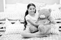 Favorite toy. Girl child sit on bed hug teddy bear in her bedroom. Kid prepare to go to bed. Pleasant time in cozy Royalty Free Stock Photo