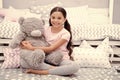 Favorite toy. Girl child sit on bed hug teddy bear in her bedroom. Kid prepare to go to bed. Pleasant time in cozy Royalty Free Stock Photo