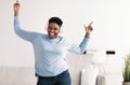 Joyful black woman listening to music in headphones and dancing