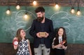 Favourite teacher concept. Man with beard and schoolgirls with school attributes. Teacher and girls pupils in classroom Royalty Free Stock Photo