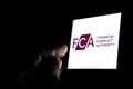 FCA Financial Conduct Authority logo on the smartphone and finger pointing at it in the dark room. Concept. Royalty Free Stock Photo