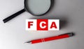 FCA word on wooden cubes with pen and magnifier Royalty Free Stock Photo