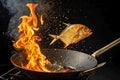 A fish is being fried in a large, round wok with a wooden handle. Royalty Free Stock Photo