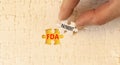 FDA Food and Drug Administration payment symbol. Concept words FDA payment on beautiful white puzzle. Beautiful yellow table Royalty Free Stock Photo