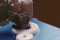 FDM-3D-printer with blue print platform manufactures white helical gears from plastic filament in bright sunny light