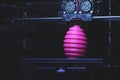 FDM 3D-printer manufacturing wound pink easter egg sculpture - front view on object and print head