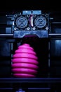 FDM 3D-printer manufacturing wound pink easter egg sculpture - front view on object and print head - portrait composition