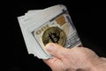 Feale hand holds bitcoin and dollar bills on black background