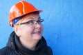 Feamle Engineer in the construction helmet on blue background, closeup