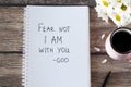 Fear not I am with you, God, handwritten text in notebook with flowers and cup of coffee on wooden table