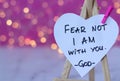 Fear not, I am with you, handwritten text verse on heart-shaped note with blurred bokeh background