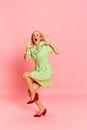 Portrait of pretty blond woman in costume spreading hands to side and screaming with frightening face over pink studio