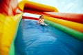 Scared Little Girl Playing on an Inflatable Slide in Amusement Park