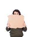 Fearful man, refugee or beggar, holding a blank cardboard sheet, copy space for messages. Empty banner for advertising. Homeless