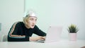 Fearful woman with aluminum hat working on laptop. Protection against 5g and mind reading and control