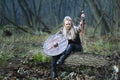 Viking woman warrior in forest with shield and sword in hand covered in blood. Royalty Free Stock Photo