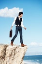 Fearless business practice. Handsome semi-formal businessman stepping towards the edge of a cliff overlooking the ocean.