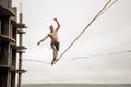 Fearless man balancing on a slackline high against empty building and sky