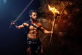 Fearless young muscular warrior with a torch in the dark