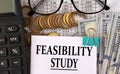FEASIBILITY STUDY - words on a white piece of paper on the background of a calculator, pennies and glasses Royalty Free Stock Photo