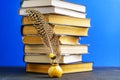 A feather in an amber inkwell against the background of a stack of books and a blue back