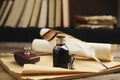 Feather pen, bottle of ink, notebook and parchment scroll on wooden table Royalty Free Stock Photo