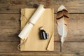 Feather pen, bottle of ink, notebook and parchment scroll on wooden table, flat lay Royalty Free Stock Photo