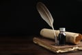 Feather pen, bottle of ink, old book and parchment scroll on wooden table. Space for text Royalty Free Stock Photo