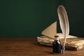 Feather pen, bottle of ink and old book on wooden table. Space for text Royalty Free Stock Photo