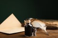 Feather pen, bottle of ink and old paper on wooden table Royalty Free Stock Photo