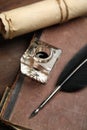 Feather pen, inkwell, old book and parchment scroll on wooden table, closeup Royalty Free Stock Photo