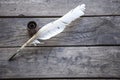 Feather for writing and inkwell .Quill for writing. The feather lies on an old wooden table with inkwell . Beautiful background Royalty Free Stock Photo