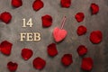 FEB 14, Valentine`s Day. Red rose petals and heart on adark brown rustic background. Top view, flat lay