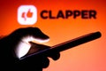 February 2, 2021, Brazil. In this photo illustration the Clapper logo seen in the background of a silhouette hand holding a mobile