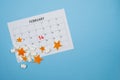 February calendar with marshmallows and star shaped orange peels on blue background with free space Royalty Free Stock Photo