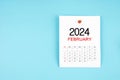 February 2024 calendar page with push pin on blue background Royalty Free Stock Photo